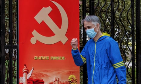 A masked man passes by a Chinese Communist party poster in Shanghai, where a number of residential communities have been put under lockdown.